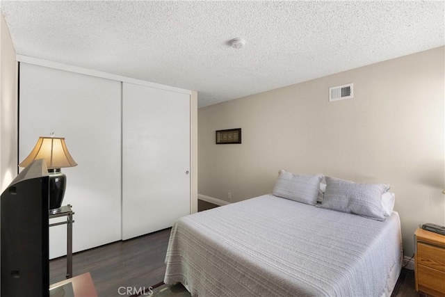 bedroom featuring dark wood-type flooring, a closet, and a textured ceiling