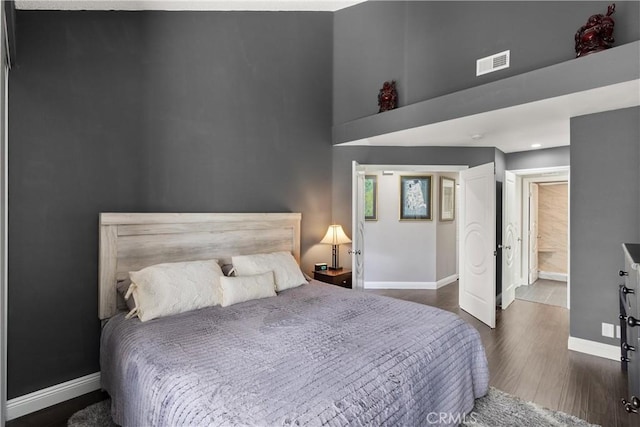 bedroom with dark hardwood / wood-style floors and a high ceiling