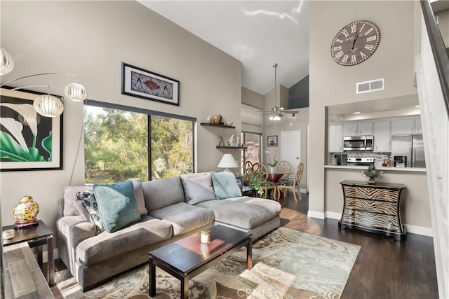 living room with ceiling fan, dark hardwood / wood-style floors, and high vaulted ceiling