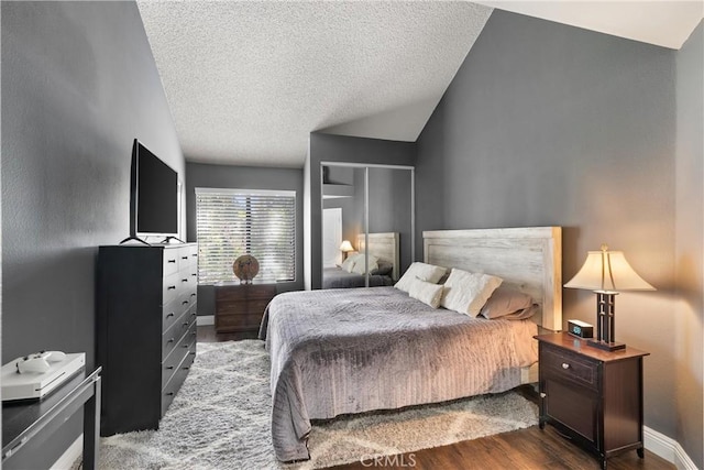 bedroom featuring lofted ceiling, dark wood-type flooring, and a textured ceiling