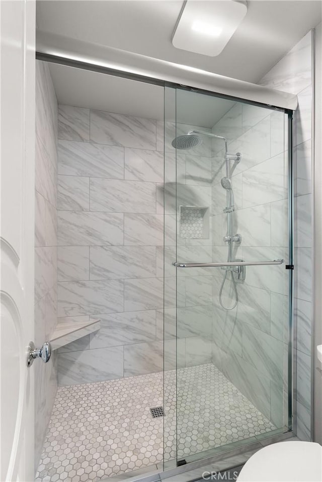 bathroom with a shower with shower door and toilet