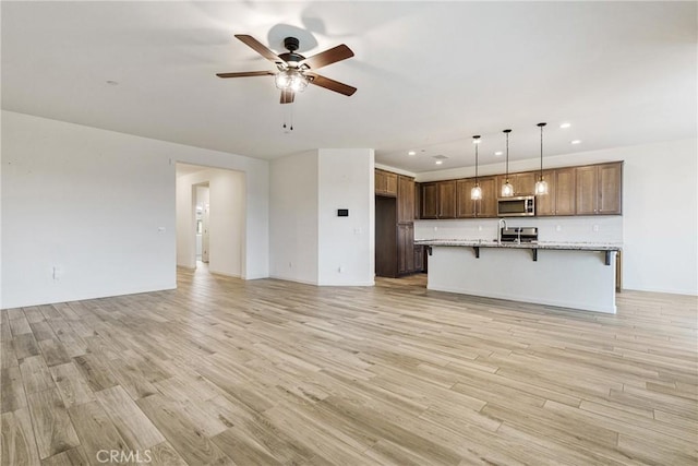 unfurnished living room with a sink, light wood-style floors, a ceiling fan, and recessed lighting