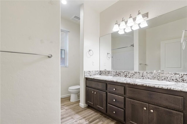 bathroom with double vanity, visible vents, a sink, and wood finished floors