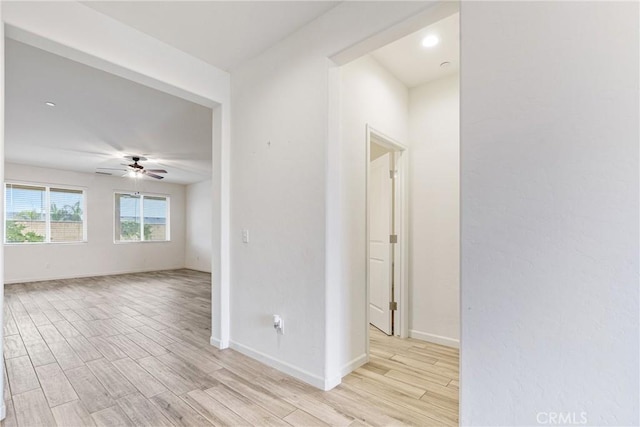 empty room with baseboards, a ceiling fan, and light wood-style floors