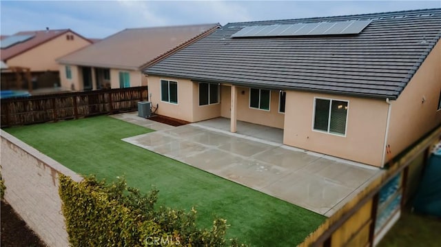 rear view of house with a patio, central AC unit, a fenced backyard, a yard, and stucco siding