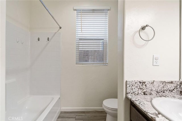 bathroom featuring bathing tub / shower combination, toilet, vanity, wood finished floors, and baseboards