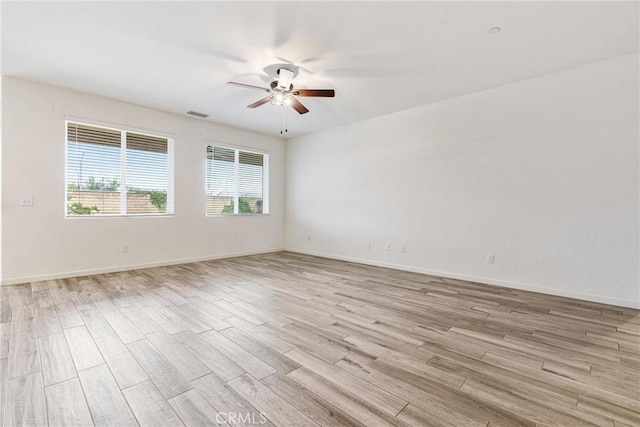 unfurnished room featuring a ceiling fan, light wood-type flooring, visible vents, and baseboards