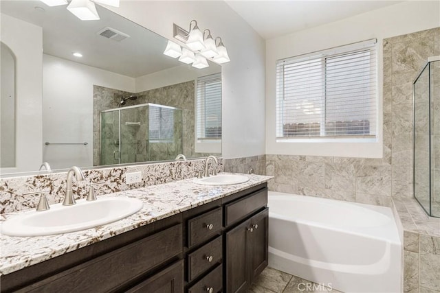 bathroom featuring a bath, a stall shower, a sink, and visible vents