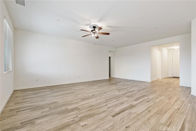 spare room featuring light wood finished floors, ceiling fan, visible vents, and baseboards