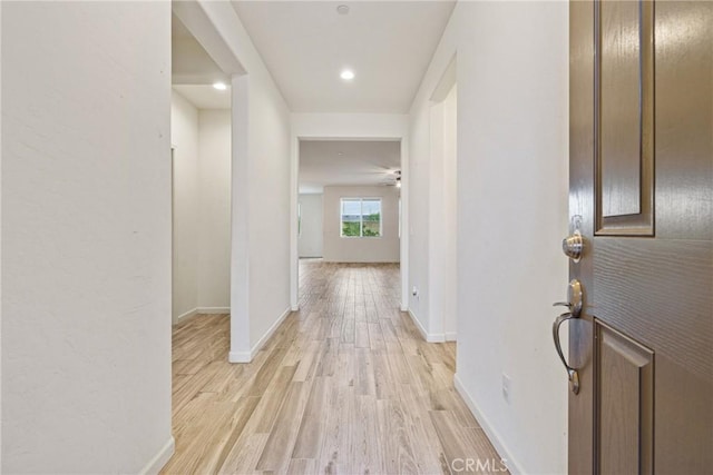 hall with light wood-style floors, baseboards, and recessed lighting