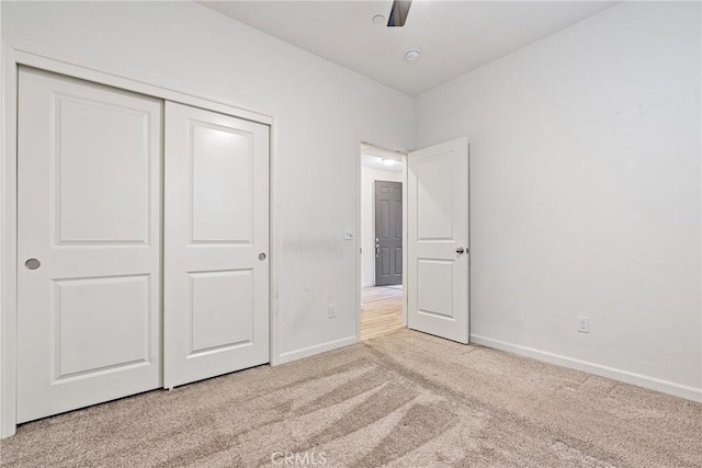 unfurnished bedroom with light carpet, ceiling fan, baseboards, and a closet