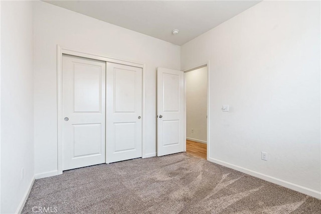 unfurnished bedroom with carpet, a closet, and baseboards