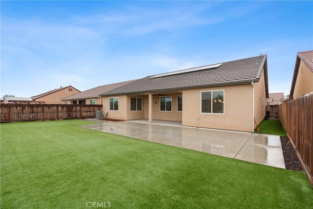 rear view of property featuring solar panels, stucco siding, a lawn, a patio area, and a fenced backyard