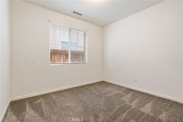 unfurnished room with carpet floors, visible vents, and baseboards