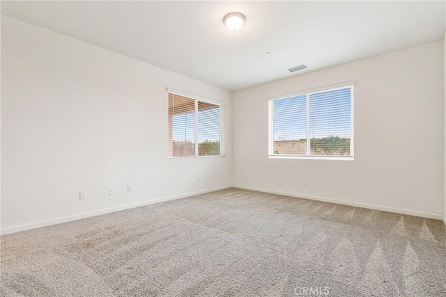 carpeted empty room featuring baseboards and visible vents