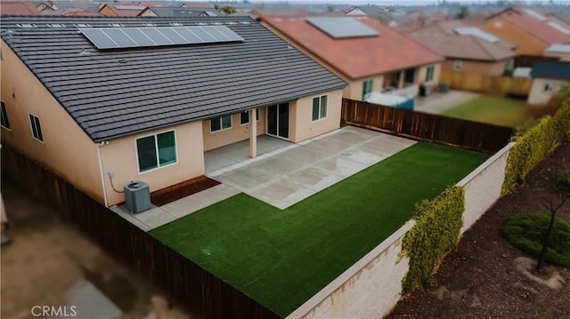 rear view of property with a lawn, a fenced backyard, a patio area, central AC, and stucco siding