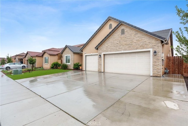 single story home featuring an attached garage, fence, a tile roof, driveway, and stone siding