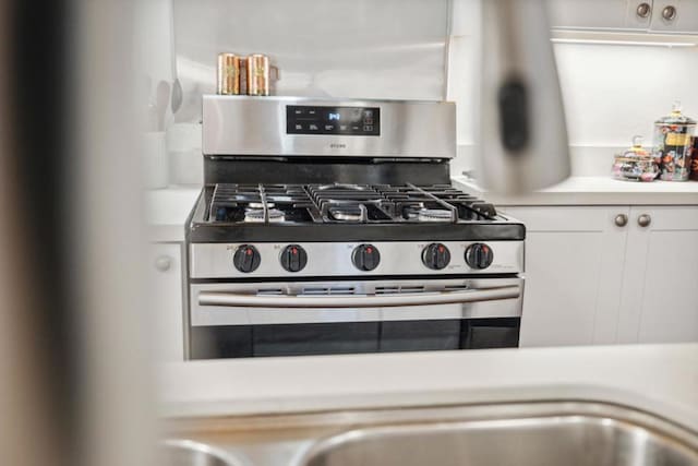 kitchen featuring stainless steel gas range and white cabinets