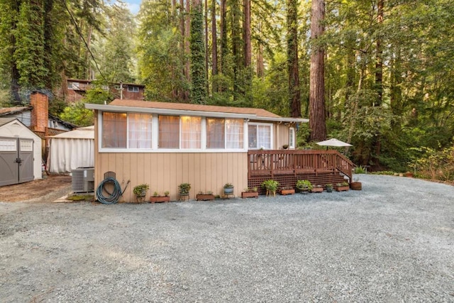 view of front of house featuring a wooden deck, a shed, and central air condition unit