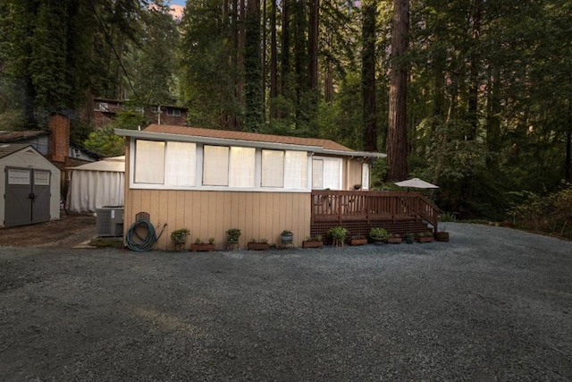 view of home's exterior with a deck, a shed, and central air condition unit