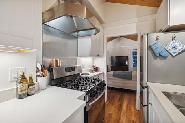 kitchen with dark wood-type flooring, wall chimney exhaust hood, vaulted ceiling, appliances with stainless steel finishes, and white cabinets