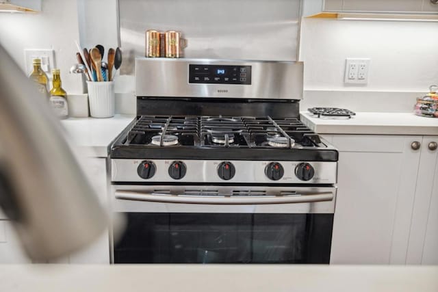 interior details featuring stainless steel gas stove and white cabinetry