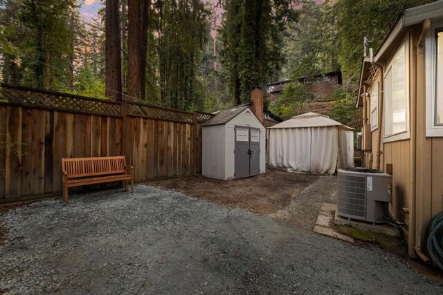 yard at dusk featuring central AC unit and a shed