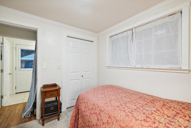 bedroom with light hardwood / wood-style flooring, ornamental molding, and a closet