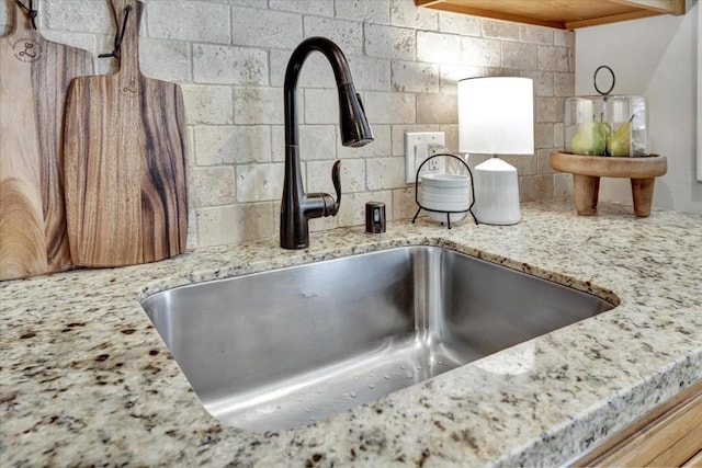 room details featuring tasteful backsplash, light stone countertops, and sink