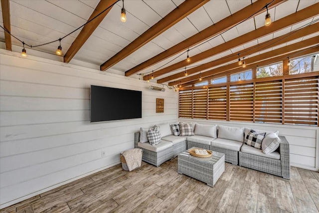 living room featuring beamed ceiling, rail lighting, hardwood / wood-style floors, and wooden walls