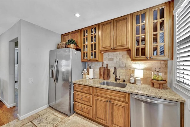 kitchen with light stone counters, appliances with stainless steel finishes, sink, and backsplash