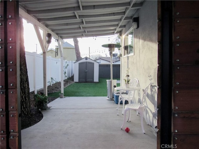 view of patio / terrace with a fenced backyard, an outdoor structure, and a storage unit