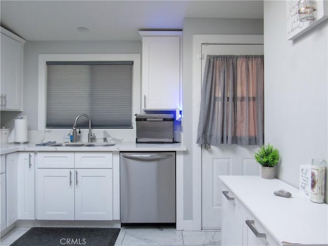 kitchen featuring light countertops, stainless steel dishwasher, a sink, and white cabinets