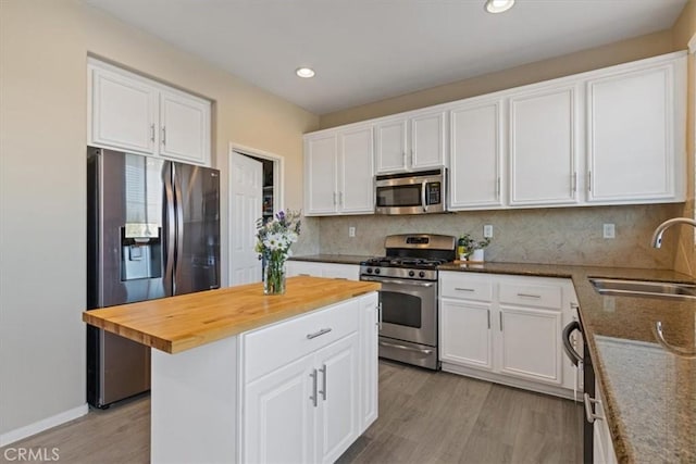 kitchen featuring butcher block counters, sink, white cabinets, stainless steel appliances, and light wood-type flooring