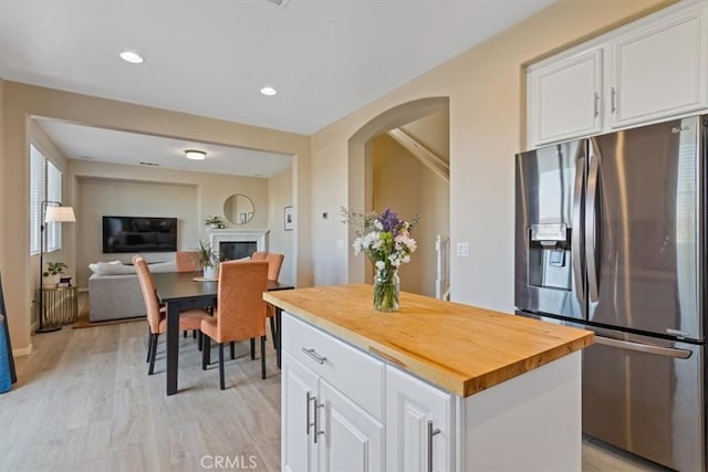 kitchen featuring butcher block countertops, white cabinetry, a center island, stainless steel refrigerator with ice dispenser, and light wood-type flooring