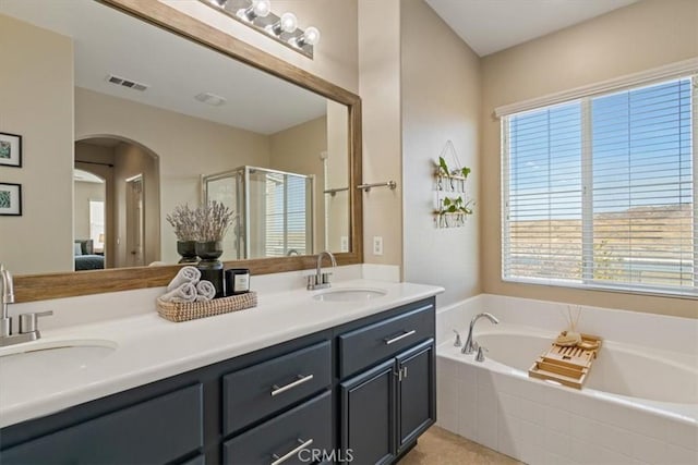 bathroom with tile patterned flooring, vanity, and plus walk in shower