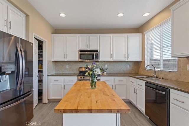 kitchen with wood counters, appliances with stainless steel finishes, a center island, and white cabinets