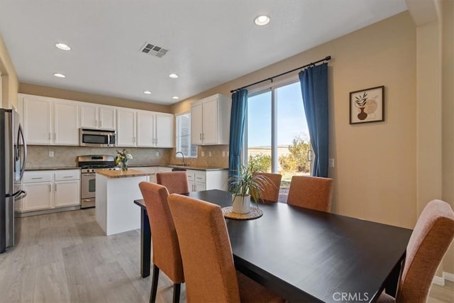 dining space with sink and light hardwood / wood-style floors