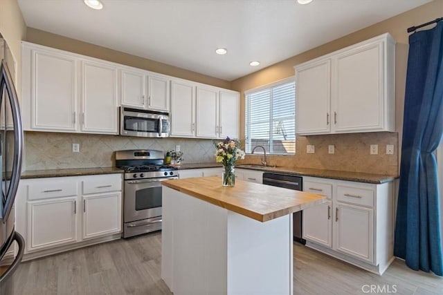 kitchen with white cabinetry, a kitchen island, wooden counters, and appliances with stainless steel finishes