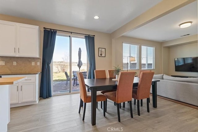 dining area with beamed ceiling and light hardwood / wood-style flooring