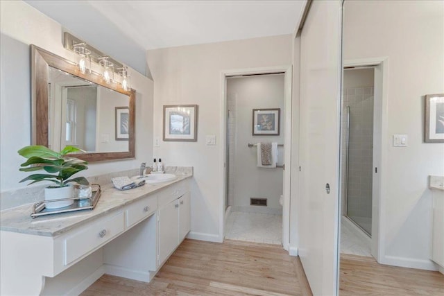 bathroom with an enclosed shower, vanity, wood-type flooring, and toilet