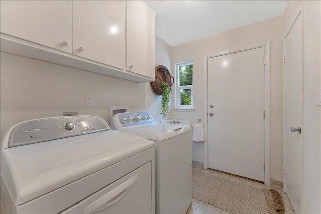 clothes washing area featuring washing machine and dryer and cabinets