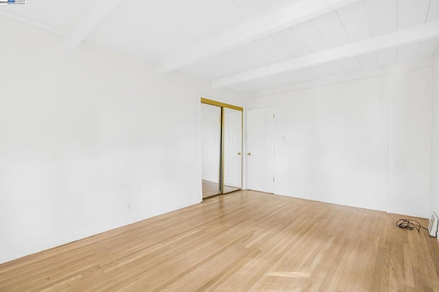 unfurnished room featuring beam ceiling and light wood-type flooring