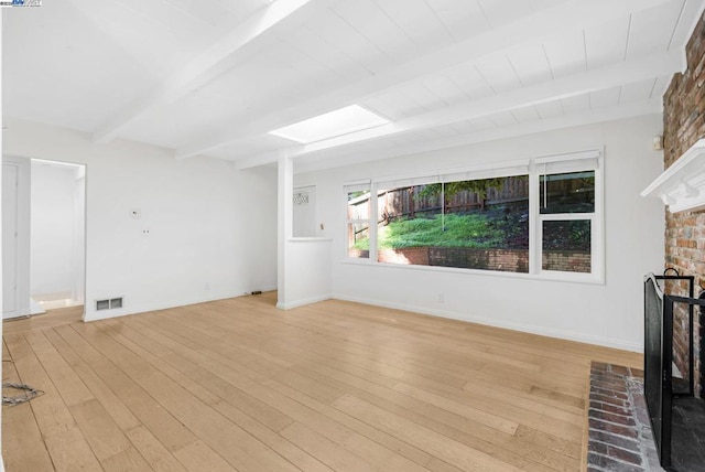 unfurnished living room with a brick fireplace, light wood-type flooring, beam ceiling, and a skylight