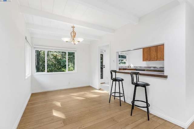 kitchen with light hardwood / wood-style flooring, a notable chandelier, plenty of natural light, and a kitchen breakfast bar