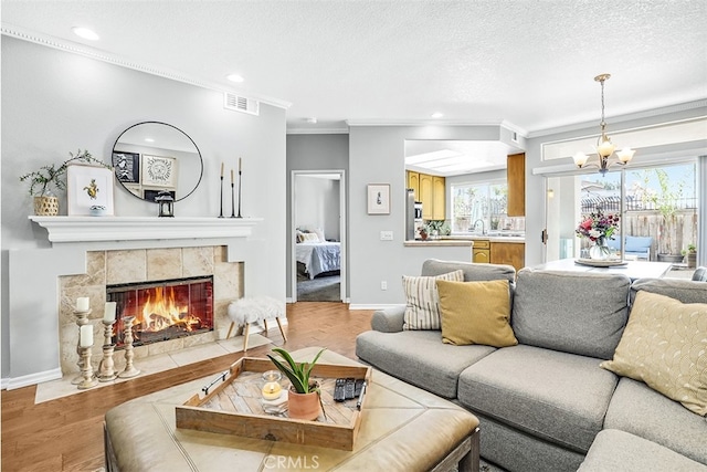 living room with baseboards, visible vents, wood finished floors, a textured ceiling, and a fireplace