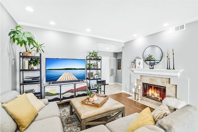 living room with hardwood / wood-style flooring, a tile fireplace, and crown molding