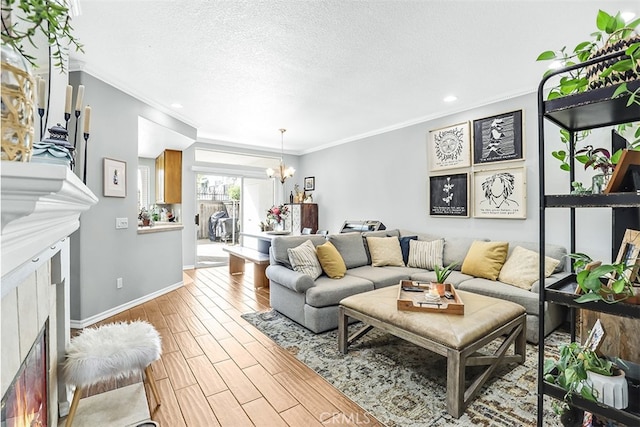 living area featuring a warm lit fireplace, ornamental molding, a textured ceiling, light wood-style floors, and a notable chandelier