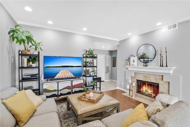 living area featuring wood finished floors, recessed lighting, a tile fireplace, and crown molding