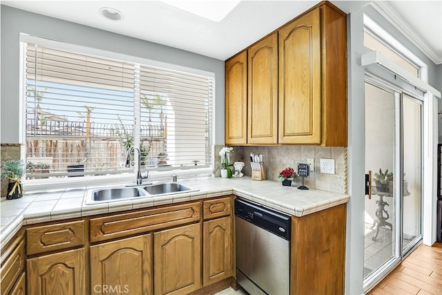 24982 La Pantera, Laguna Niguel, CA 92677 - kitchen featuring stainless steel dishwasher, brown cabinetry, light wood-style floors, backsplash, and a sink